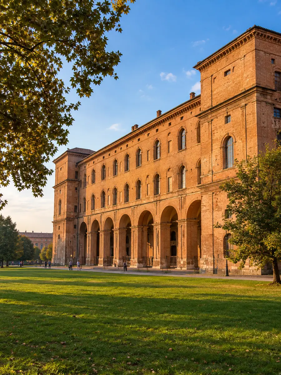 Die lange Backsteinfassade des Palazzo della Pilotta, über eine Rasenfläche hinweg im Abendlicht gesehen