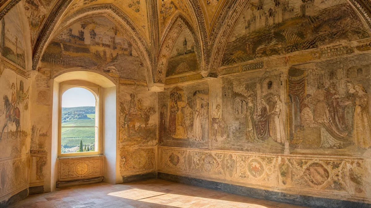 A vaulted castle chamber with faded frescoes of courtly figures and painted castles, and an arched window onto green hills