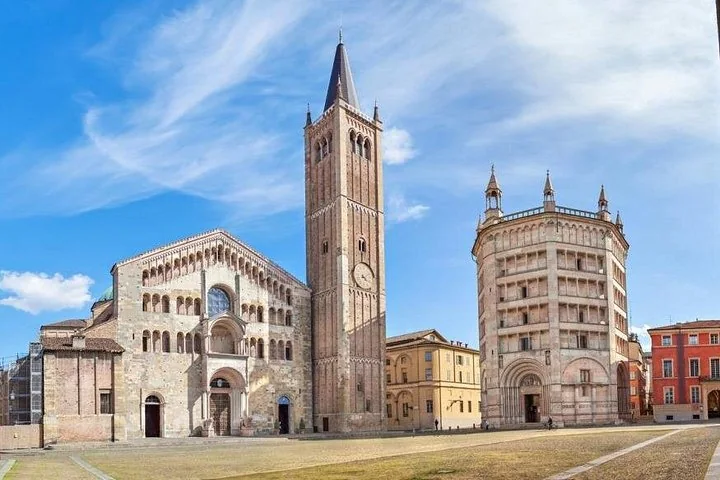 Parma's Romanesque cathedral, its tall bell tower and the octagonal pink Baptistery on a wide square under a blue sky