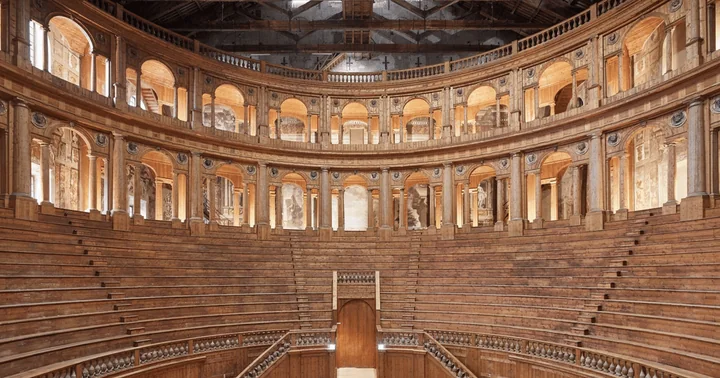 The curved wooden tiers of the Teatro Farnese rising under two storeys of arches, seen from the empty floor